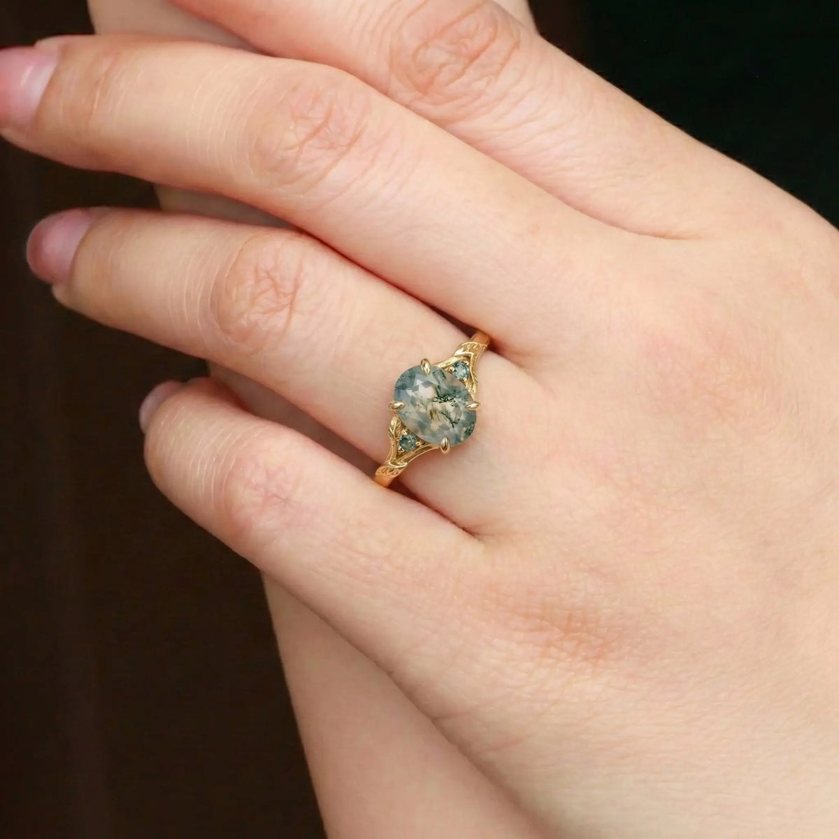Woman wearing oval moss agate leaf engagement ring