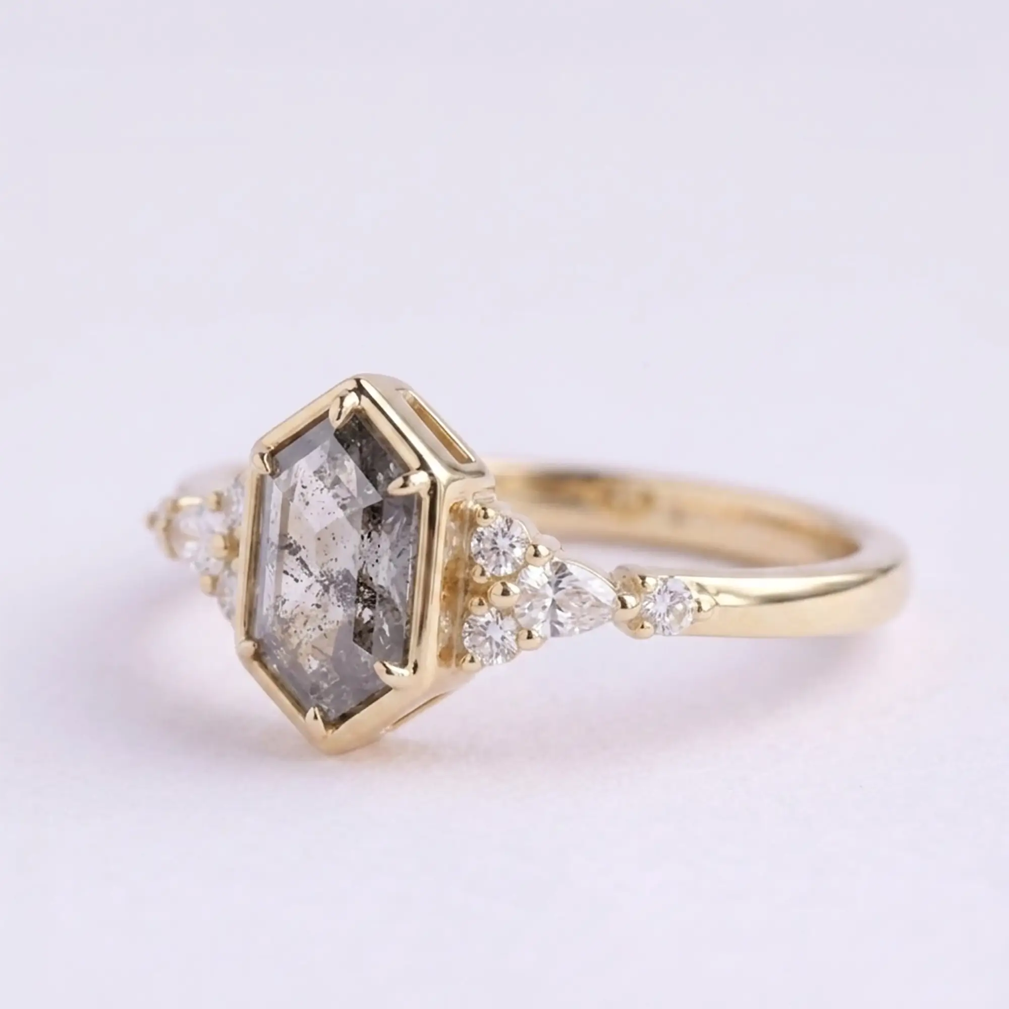 Artisanal gold ring featuring hexagon cut salt and pepper diamond and pear shaped side stones