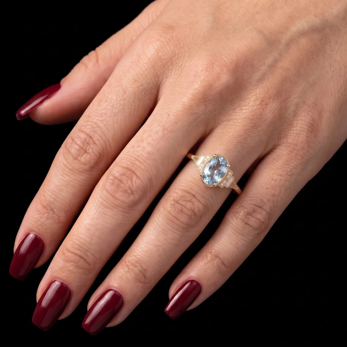 Natural oval aquamarine March birthstone engagement ring worn on hand with an elegant Art Deco yellow gold setting