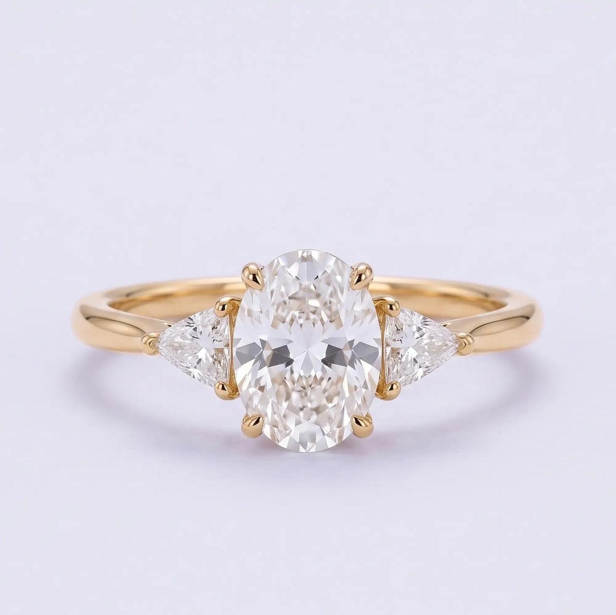 Classic oval moissanite three stone engagement ring with trillion side stones in yellow gold