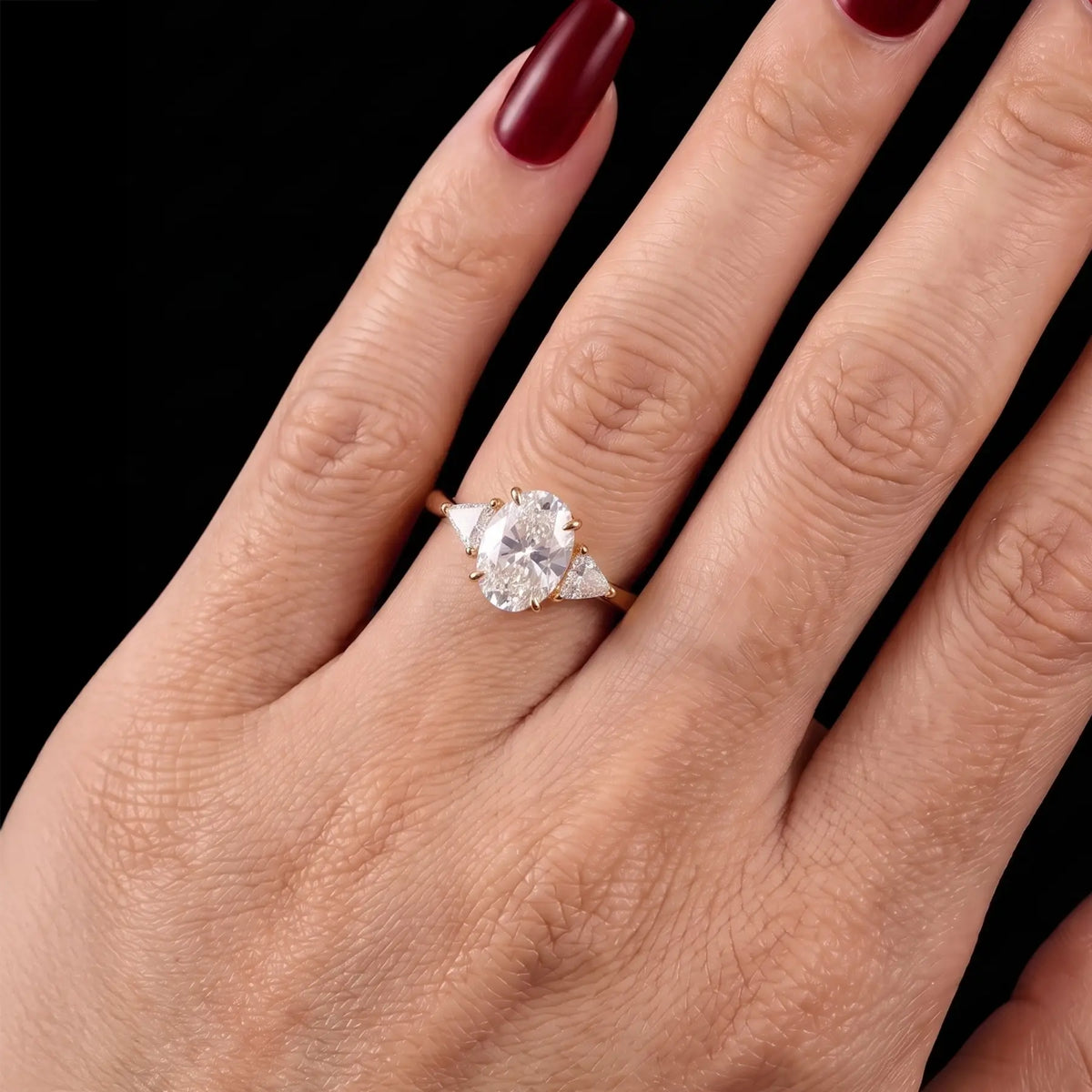 Oval moissanite three stone engagement ring worn on hand with minimalist gold design