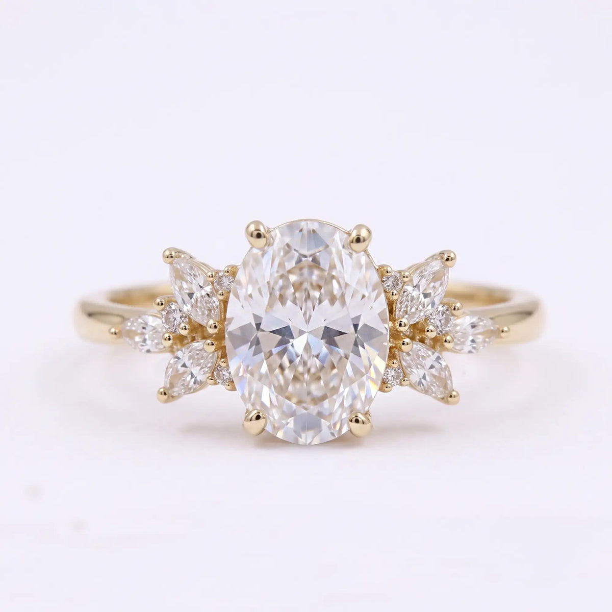 Oval cut moissanite cluster engagement ring with marquise and round accent stones in yellow gold