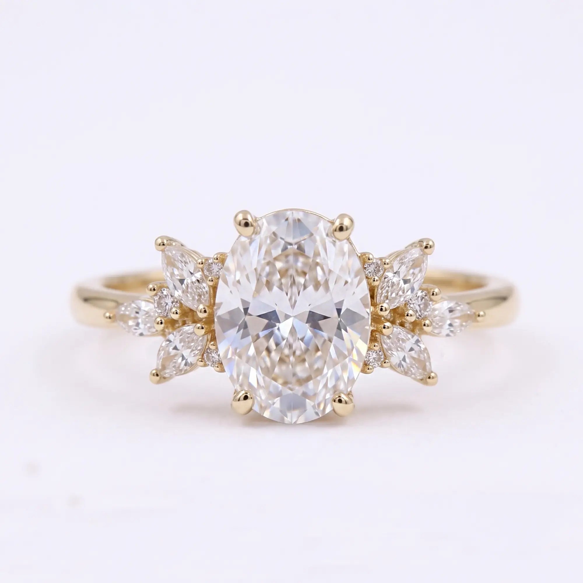Oval cut moissanite cluster engagement ring with marquise and round accent stones in yellow gold