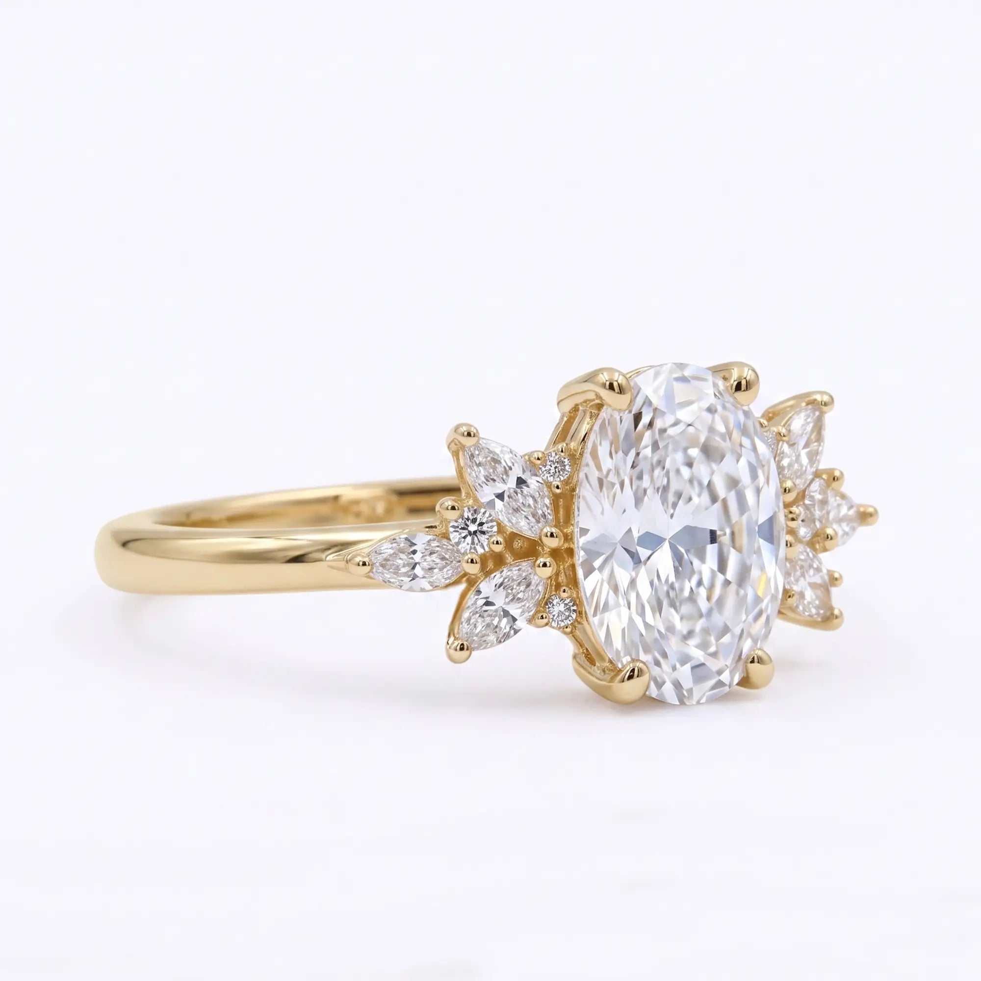 Side profile of a gold oval cut moissanite ring with sparkling cluster detail