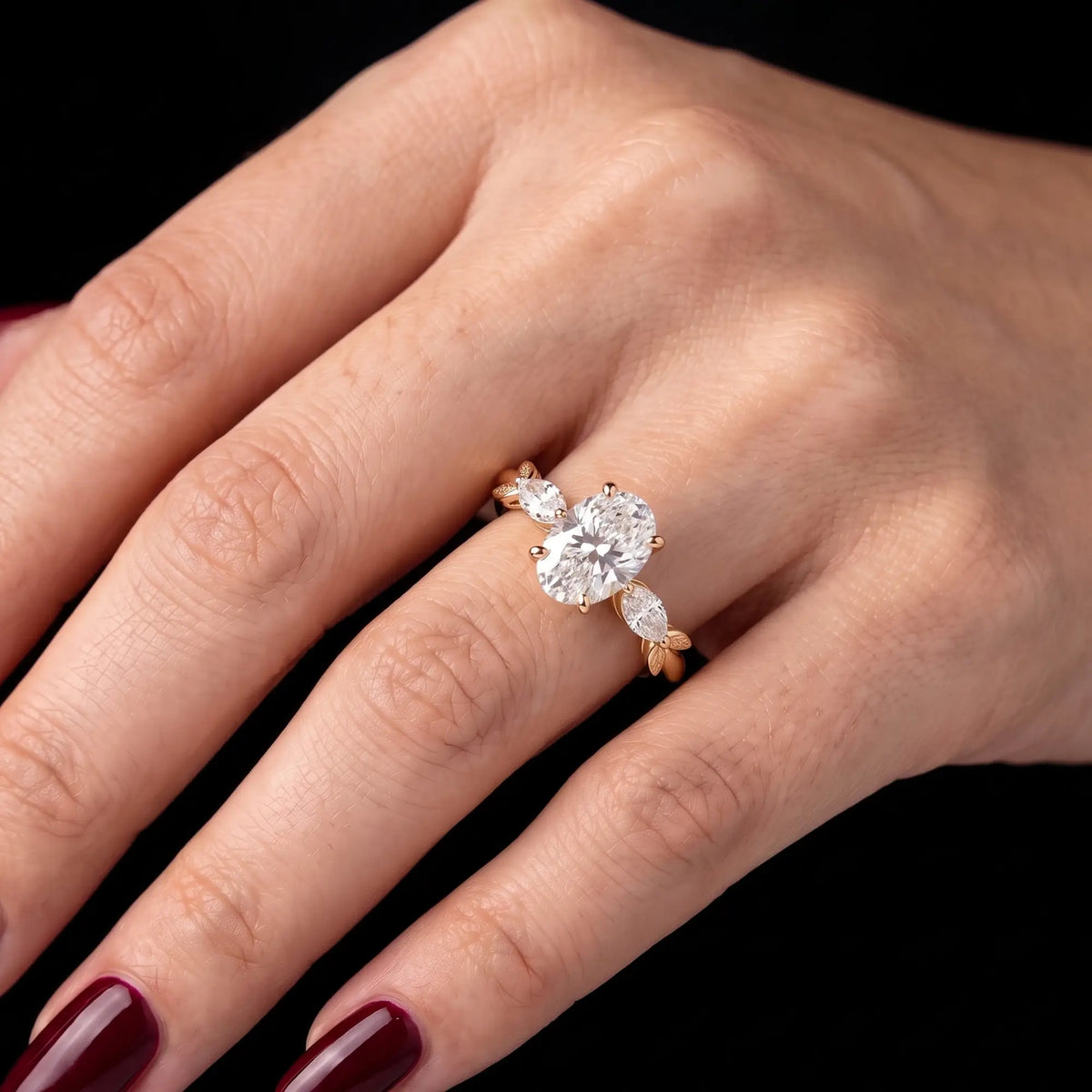 Delicate oval moissanite leaf promise ring worn on hand with a romantic three stone yellow gold setting
