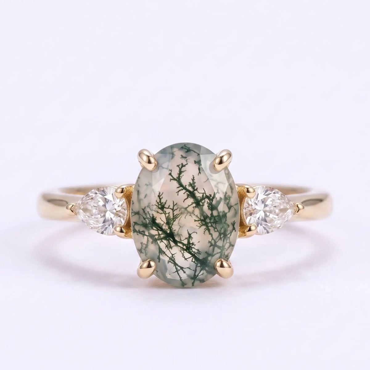 Classic oval moss agate three stone engagement ring with pear-shaped side stones in yellow gold