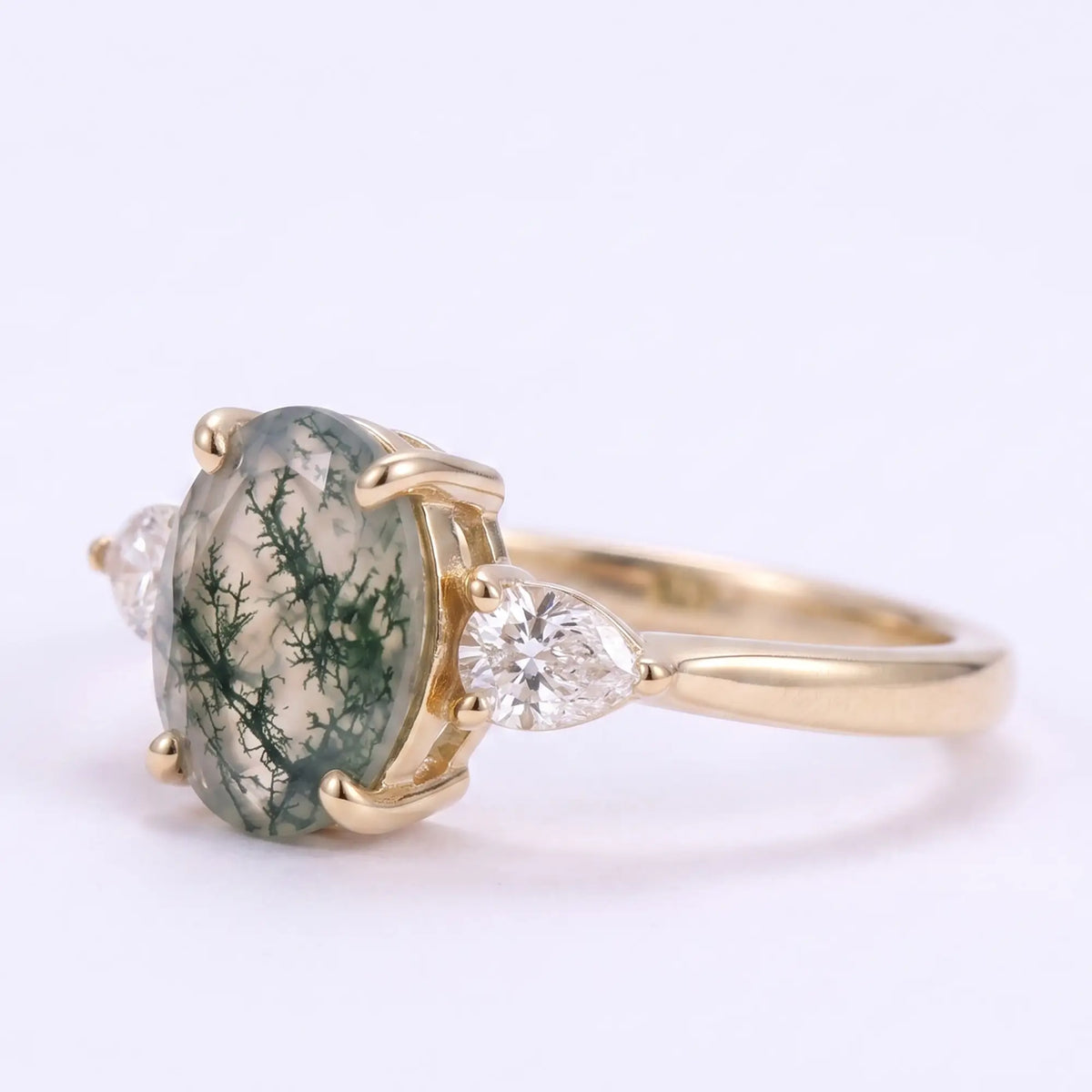 Angle view of classic moss agate engagement ring with two pear-cut side stones