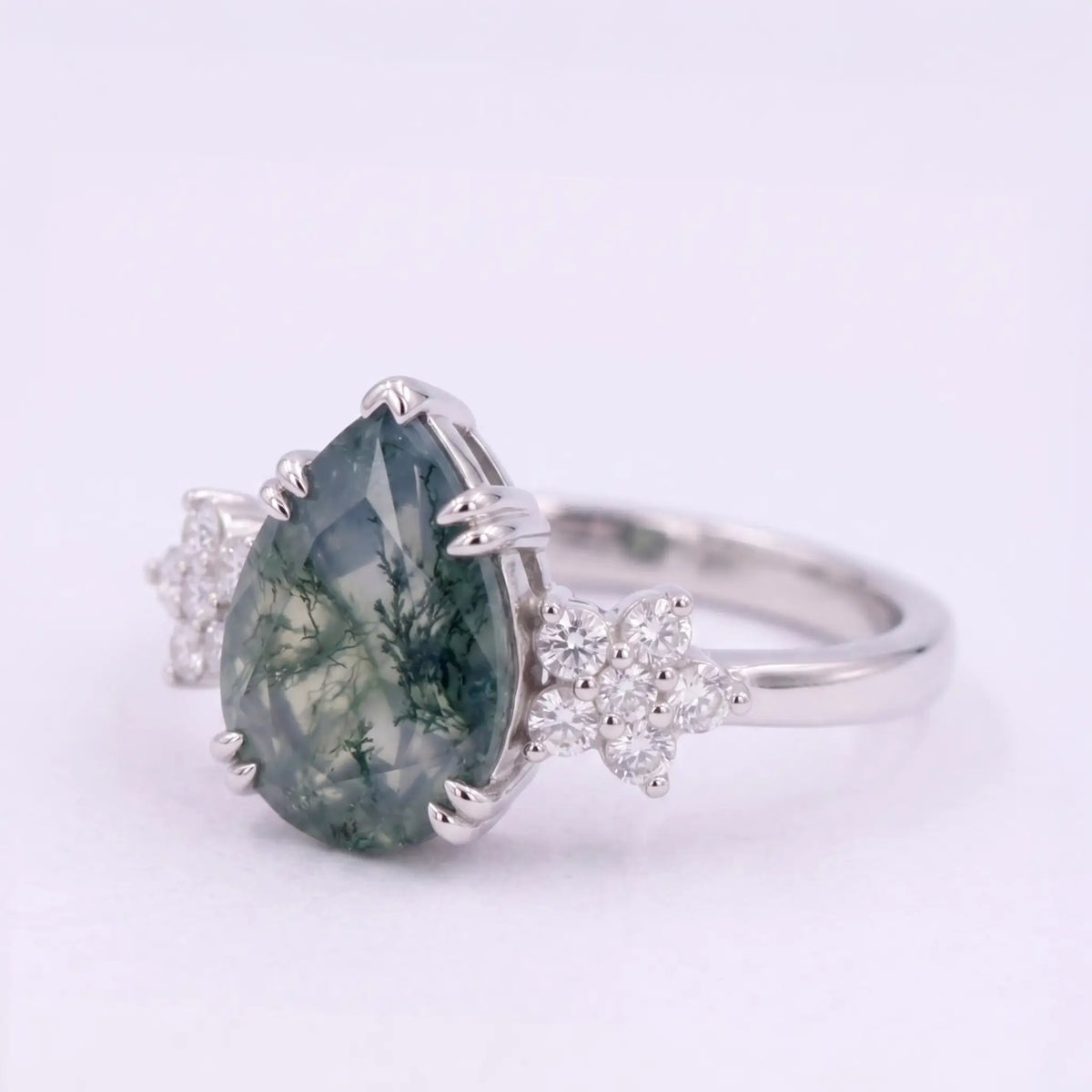 Artisanal gold ring featuring pear cut natural moss agate and delicate round moissanite floral accent
