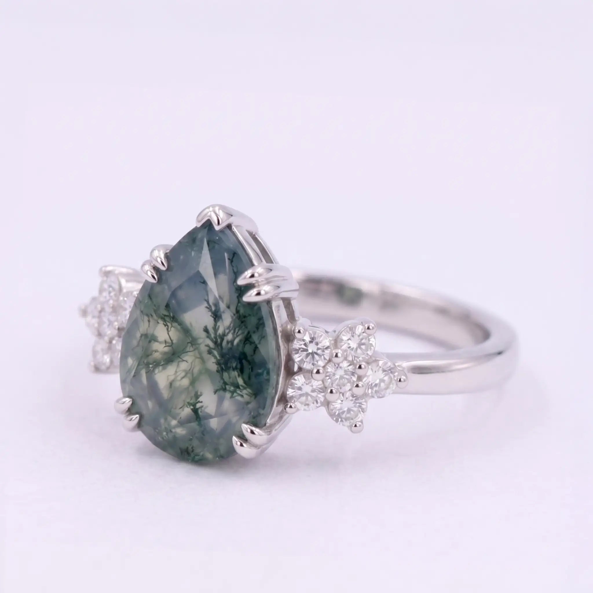 Artisanal gold ring featuring pear cut natural moss agate and delicate round moissanite floral accent