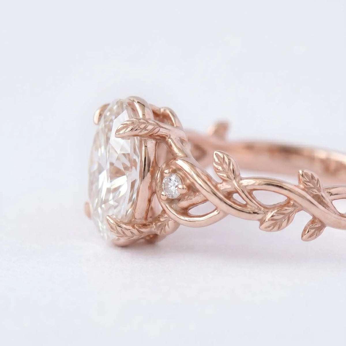Artisanal gold ring featuring oval cut moissanite held by unique decorative organic leaf prongs