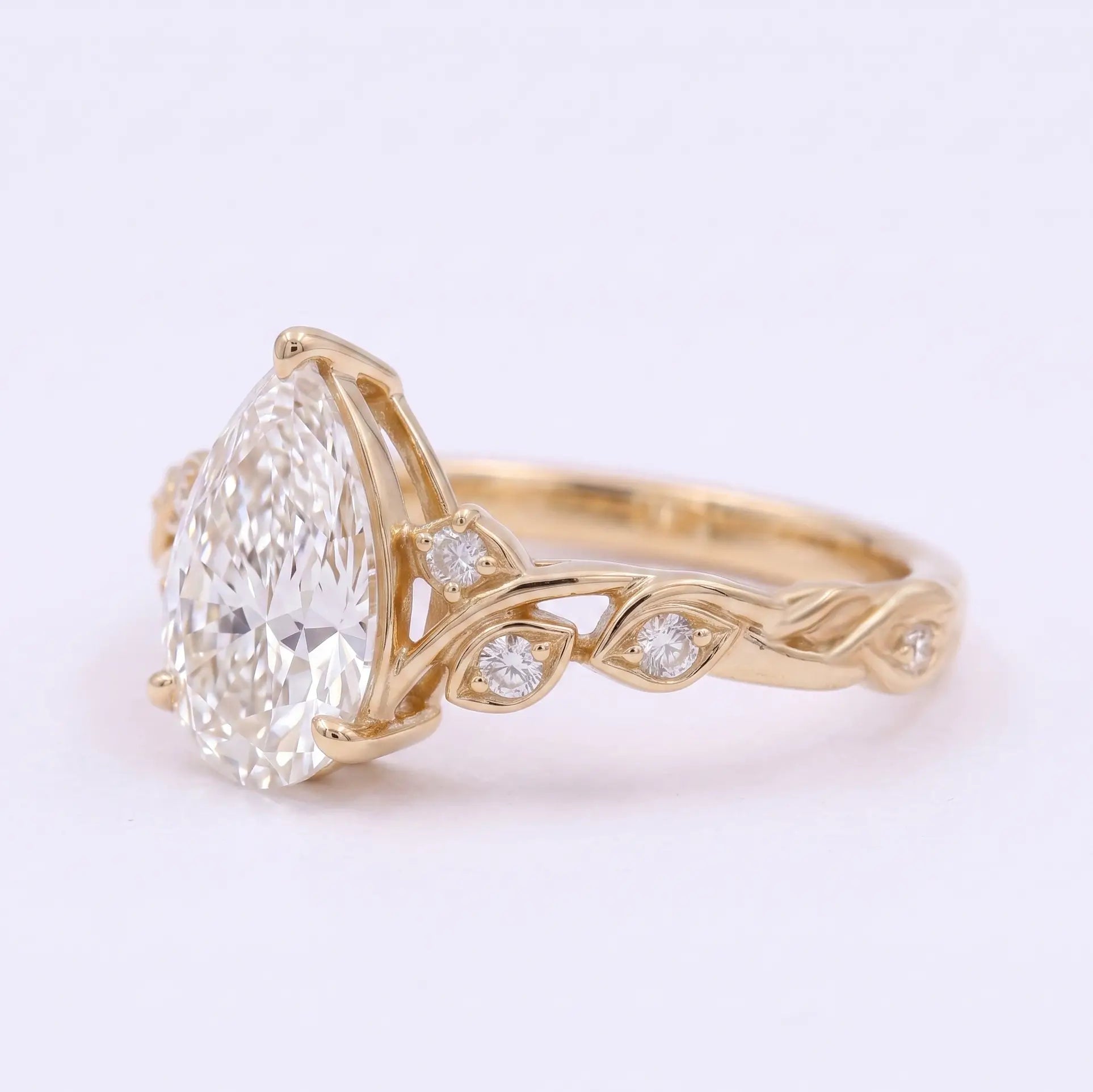 Botanical leaf engagement ring with pear cut moissanite and round side stones