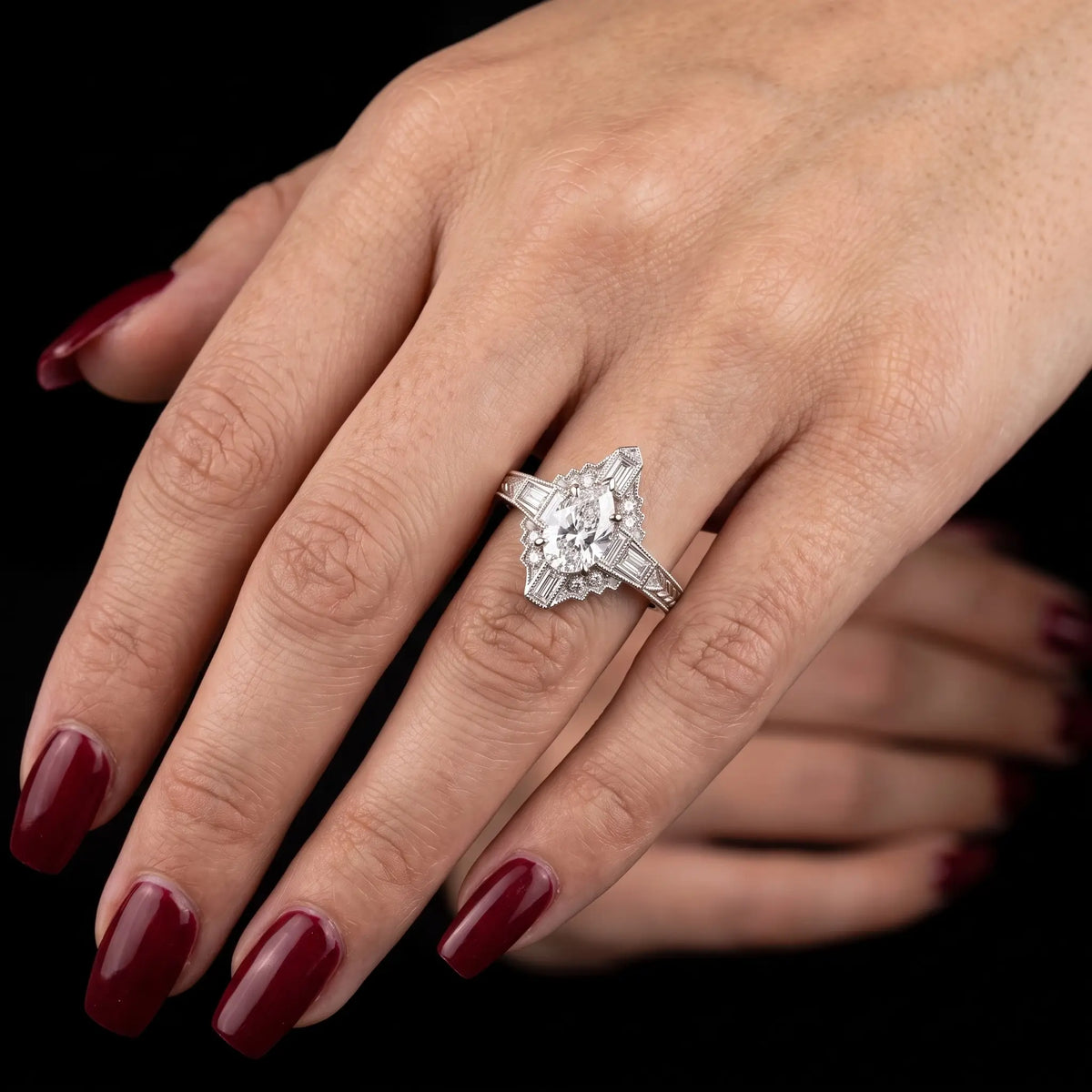 Vintage pear cut moissanite halo engagement ring worn on hand