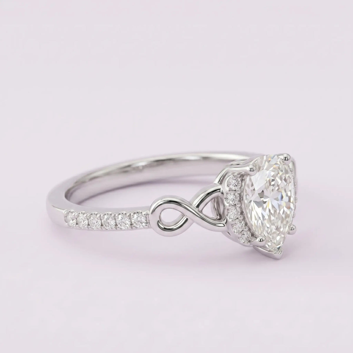 Artisanal gold ring featuring pear cut moissanite micro-halo and open-work infinity symbol accent