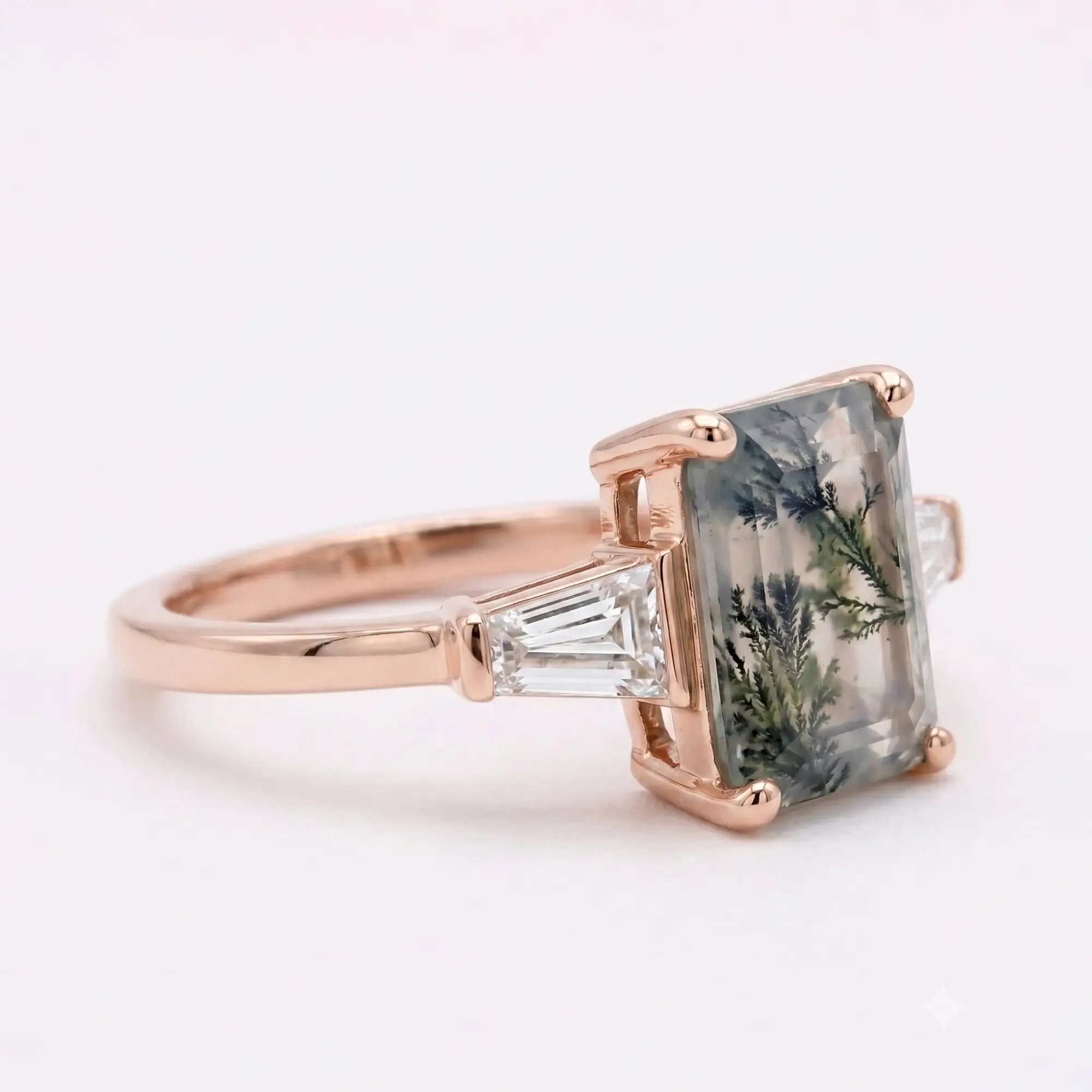 Detailed macro side view photo of an 8x6mm emerald step-cut moss agate stone showcasing organic forest-like inclusions and secure gold prongs