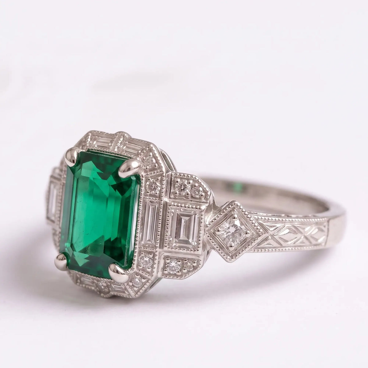Front view of lab emerald engagement ring with rectangular step-cut accents