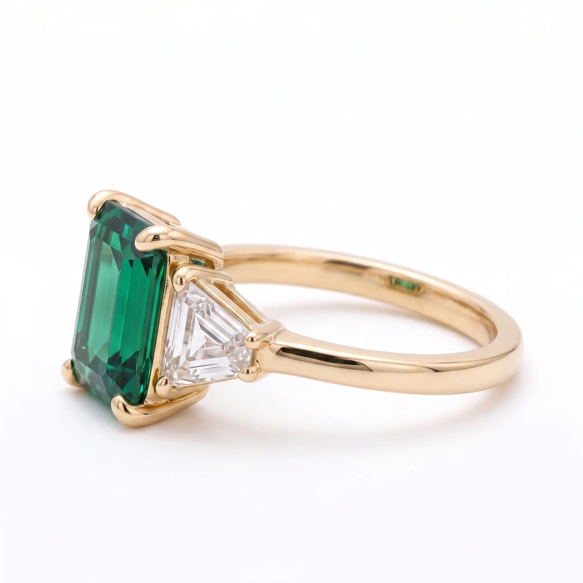 Left view of emerald cut emerald ring with trapezoid side stones