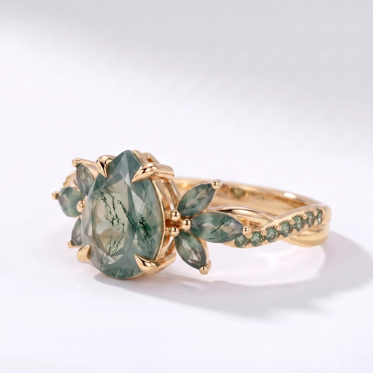 Left view of pear moss agate ring showing floral accents and curved gold band