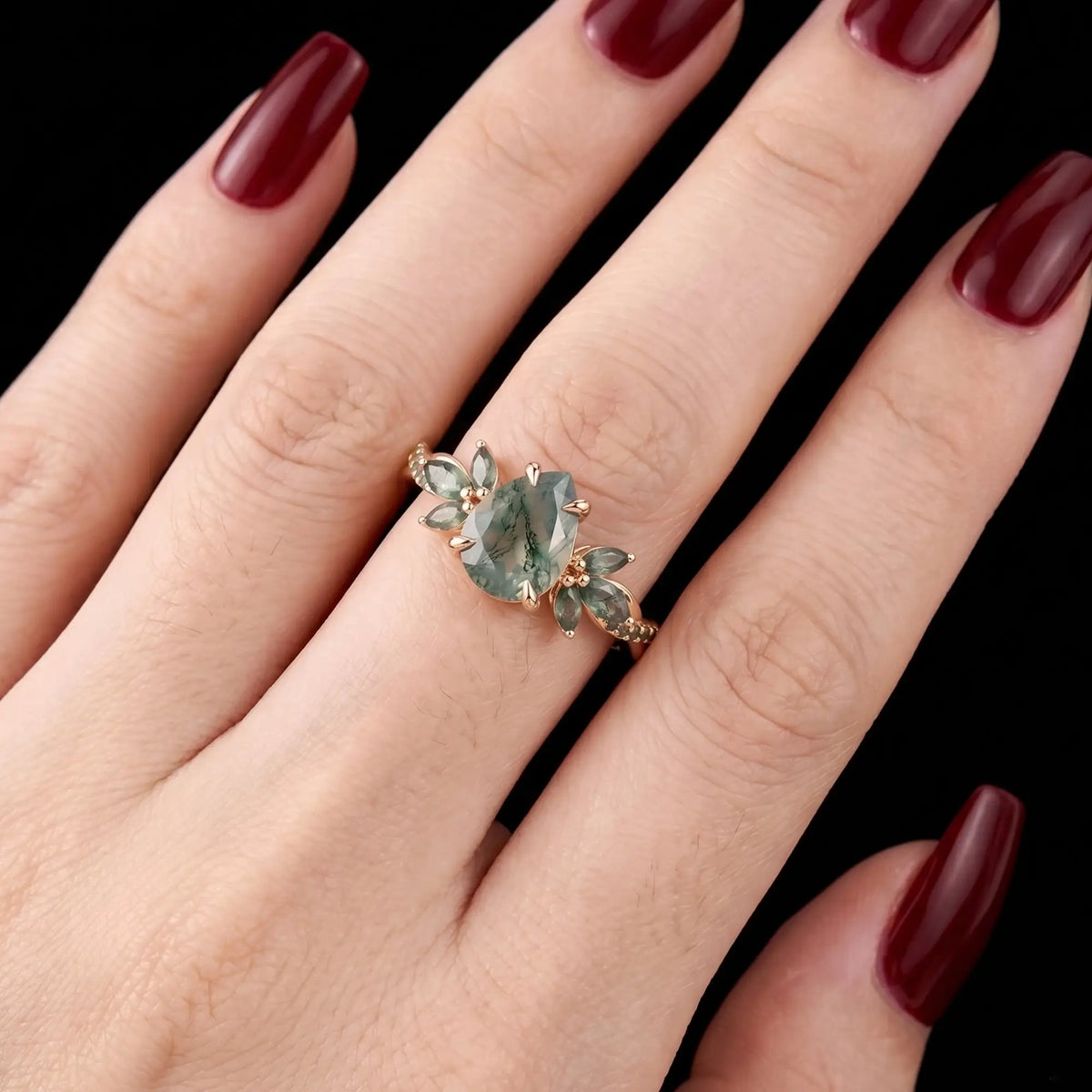 Pear moss agate engagement ring worn on hand with a floral twisted band