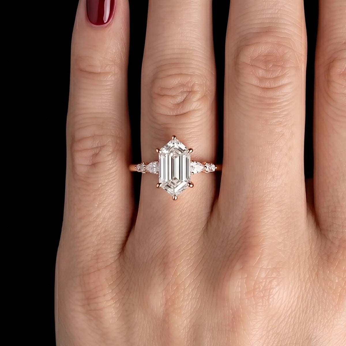 Modern alternative bridal elongated hexagon moissanite cluster ring in rose gold shown worn on a woman's finger