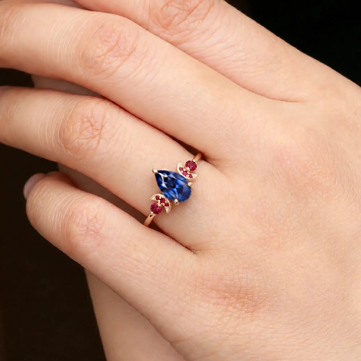 Pear cut sapphire ring worn on hand with crescent moon design details