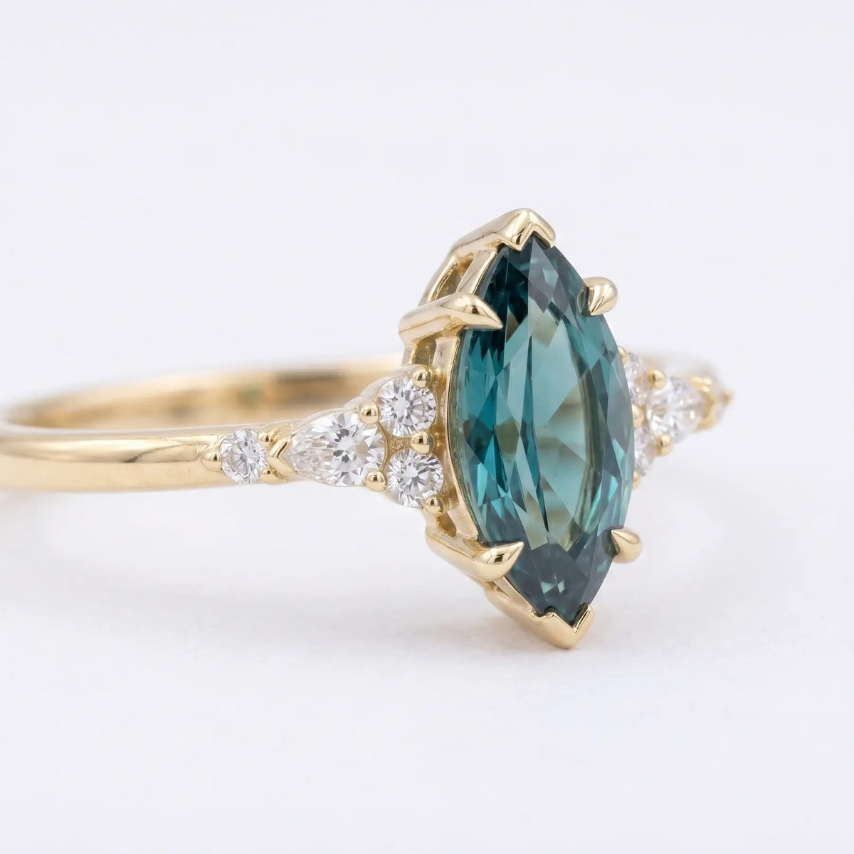 Detailed close-up of a marquise alexandrite center stone with a multi-prong V-end setting and flanking gemstone clusters