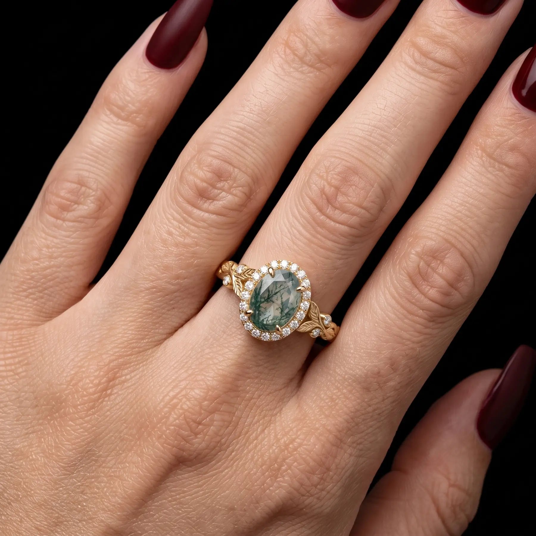 Oval moss agate leaf engagement ring worn on hand