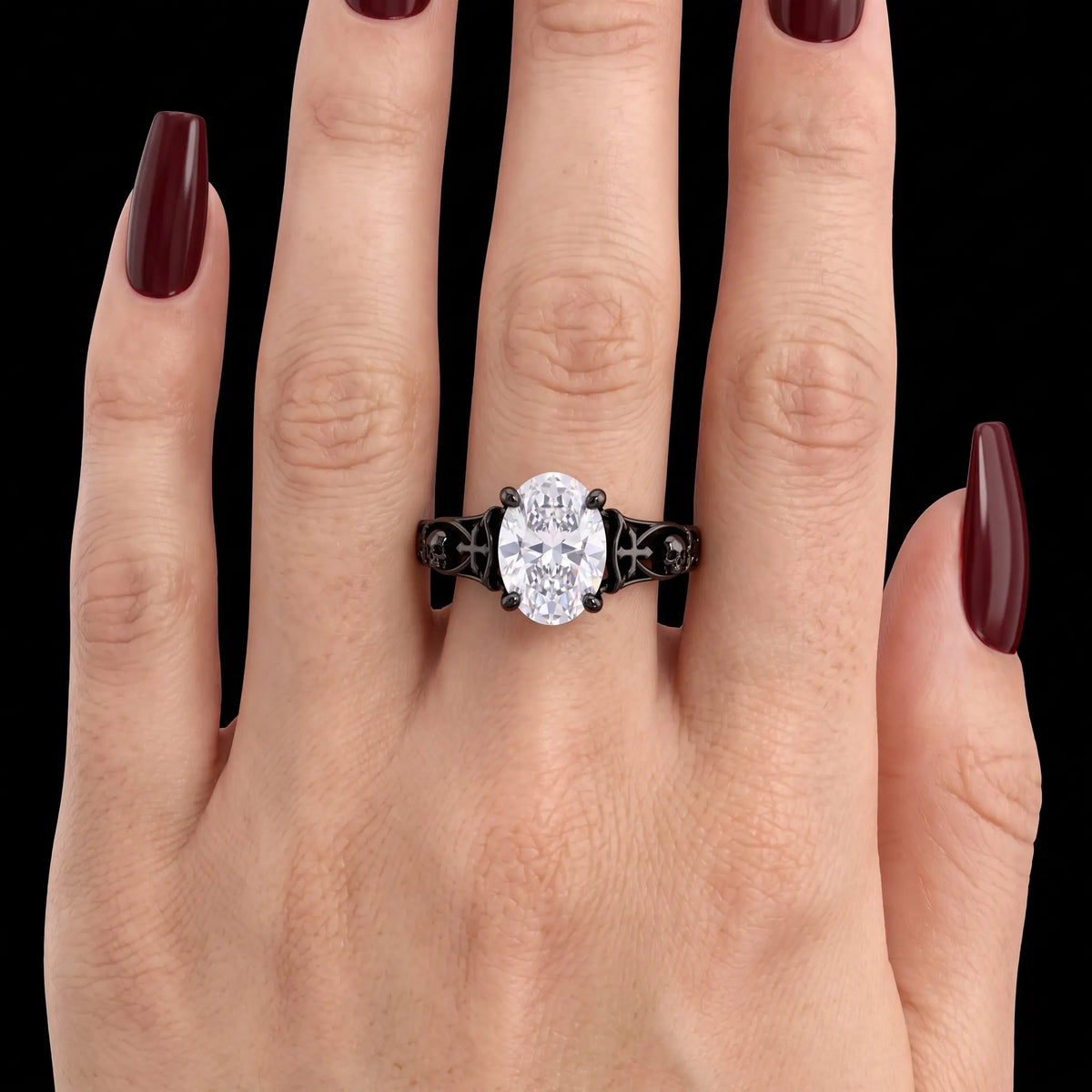 Noctivara oval lab diamond Gothic engagement ring worn on a finger, showing the black skull and cross band and its delicate proportions