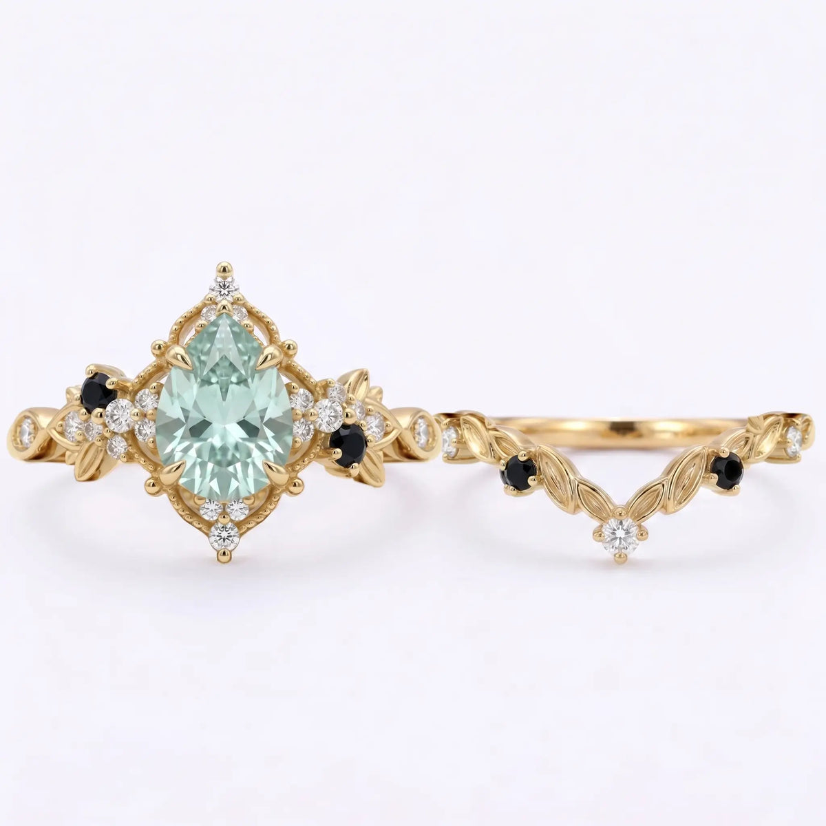 Detailed close-up view of a 6x8mm teardrop pear grey moissanite engagement ring featuring intricate gold leaf details, a halo milgrain border, and black onyx side stone accents