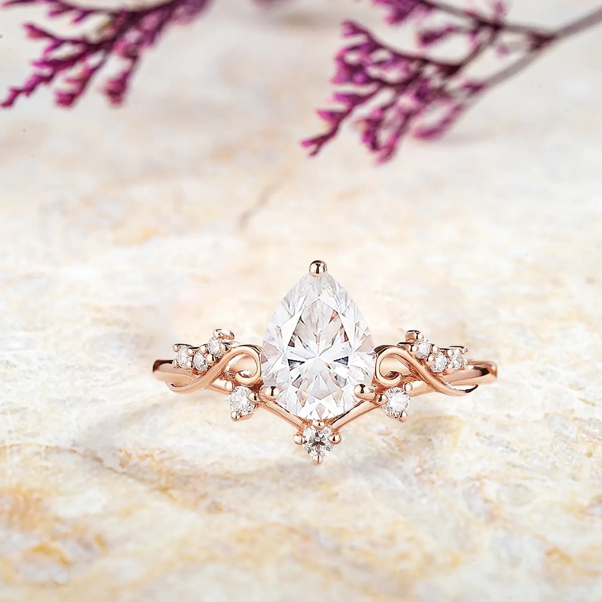 Pear moissanite engagement ring with diamond cluster and curved rose gold band vintage art deco design