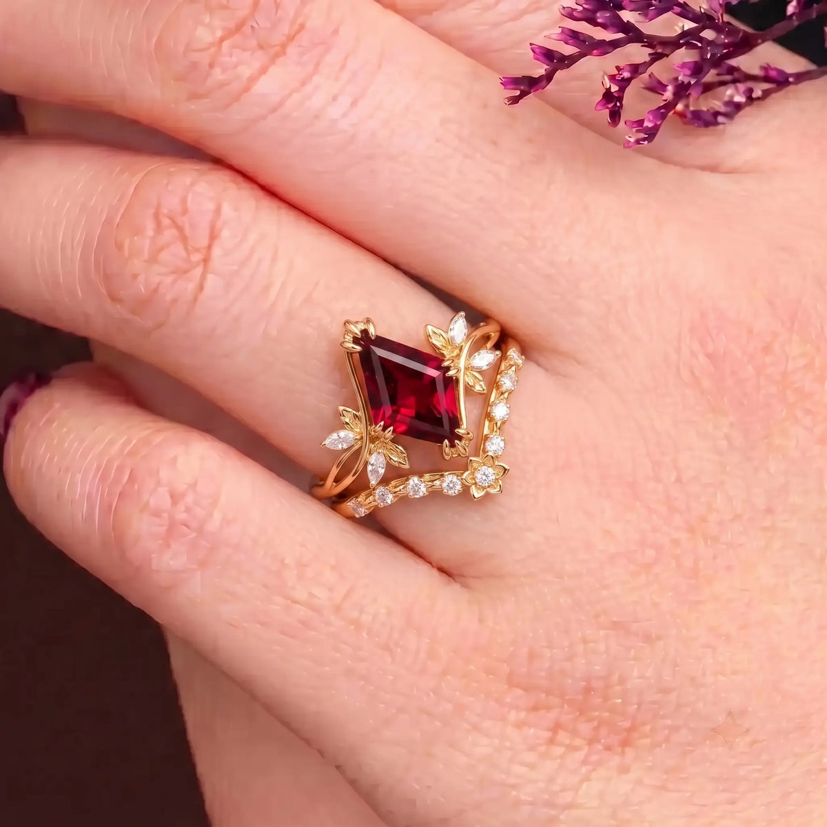 Kite cut garnet floral engagement ring worn on hand
