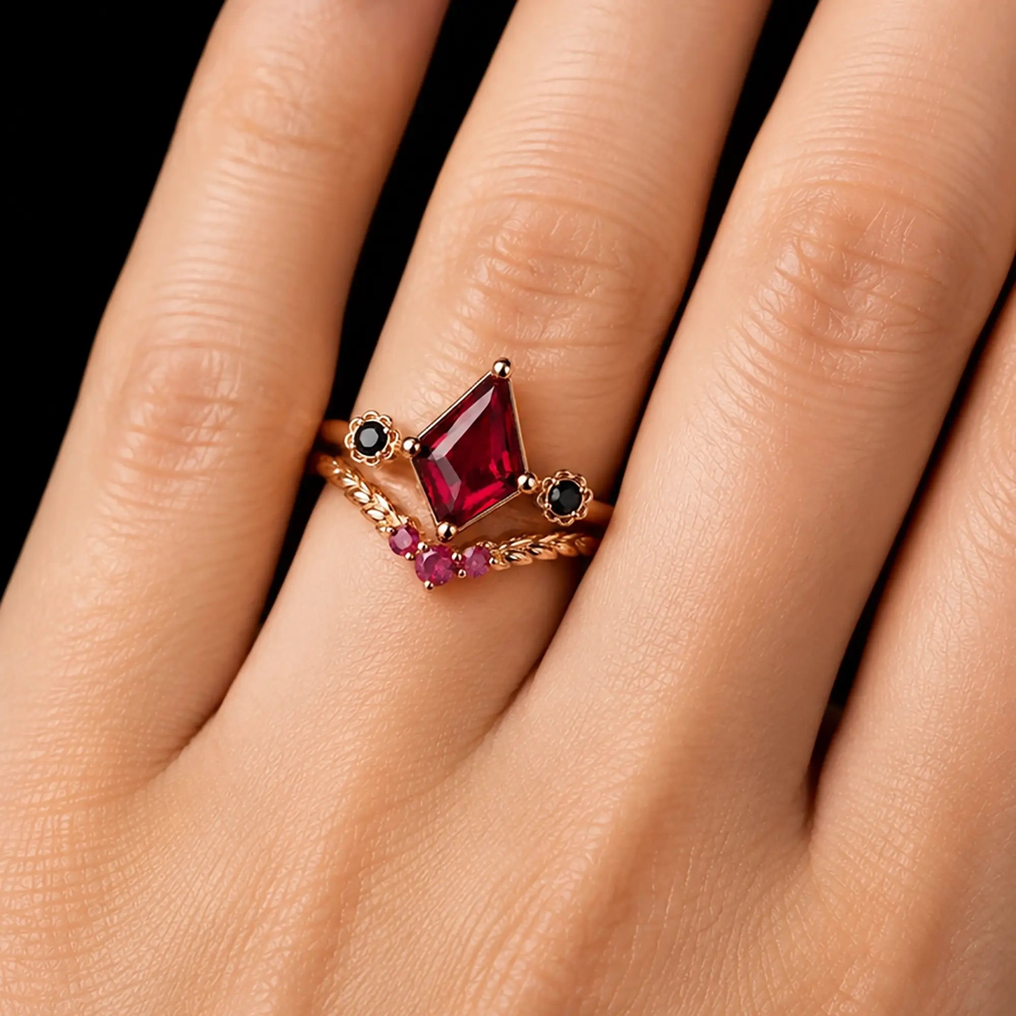 Kite cut ruby bridal ring set worn on hand with matching leaf-style wedding band
