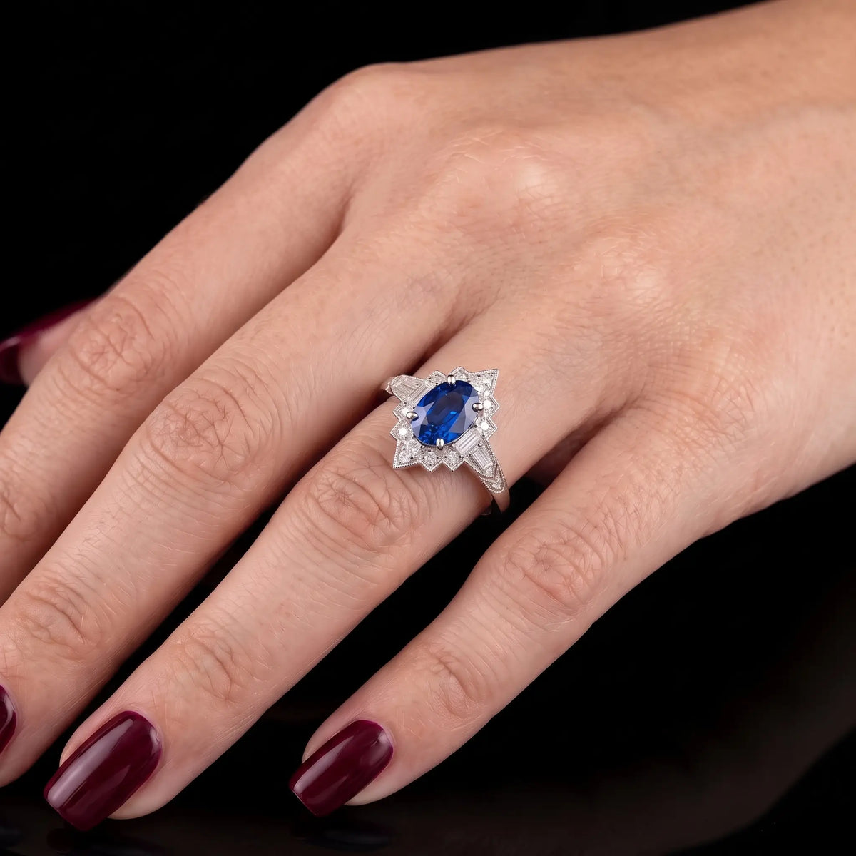 Oval sapphire Art Deco halo engagement ring worn on hand