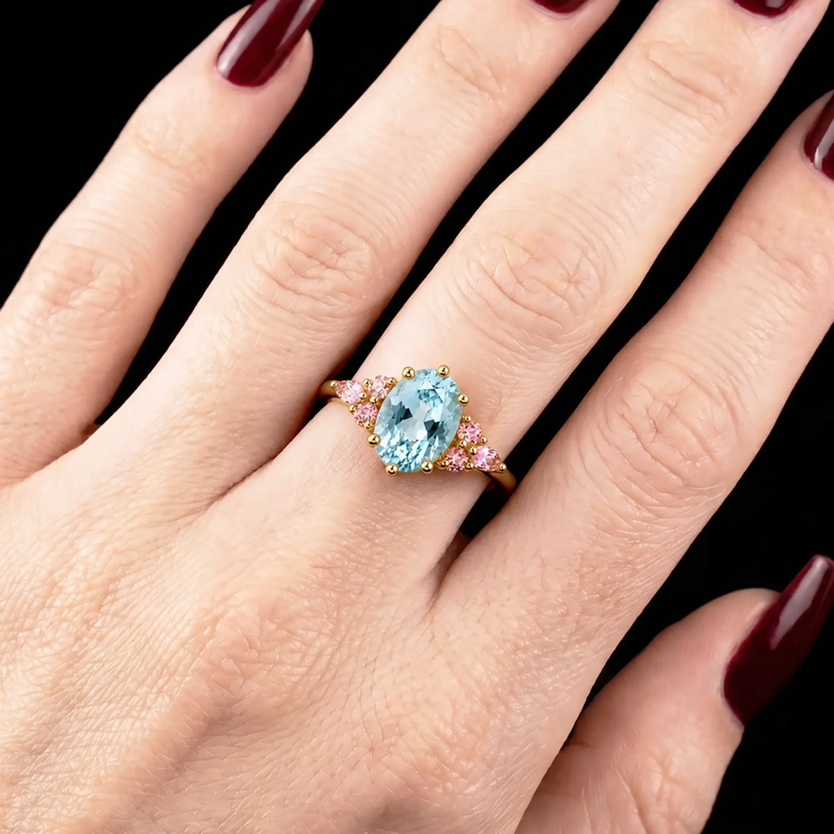 Oval aquamarine engagement ring worn on hand with delicate cluster accents