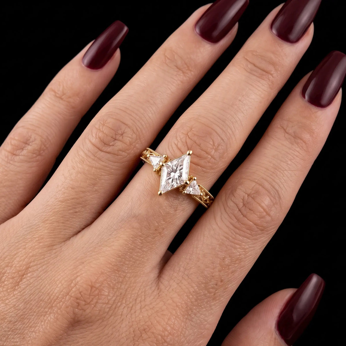 Kite cut moissanite three stone engagement ring with leaf design worn on hand