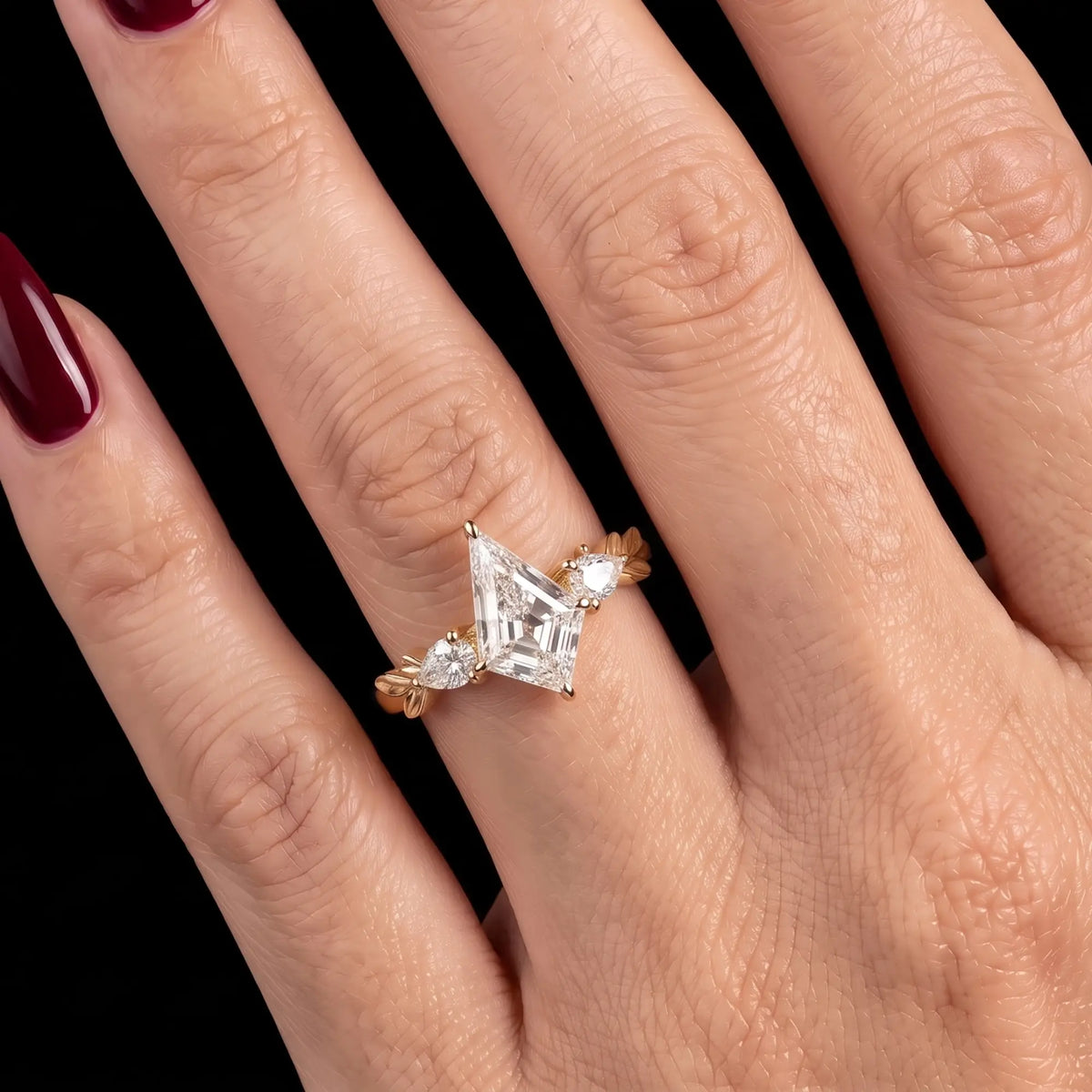 Kite cut moissanite leaf engagement ring worn on hand showing its romantic three stone design in yellow gold