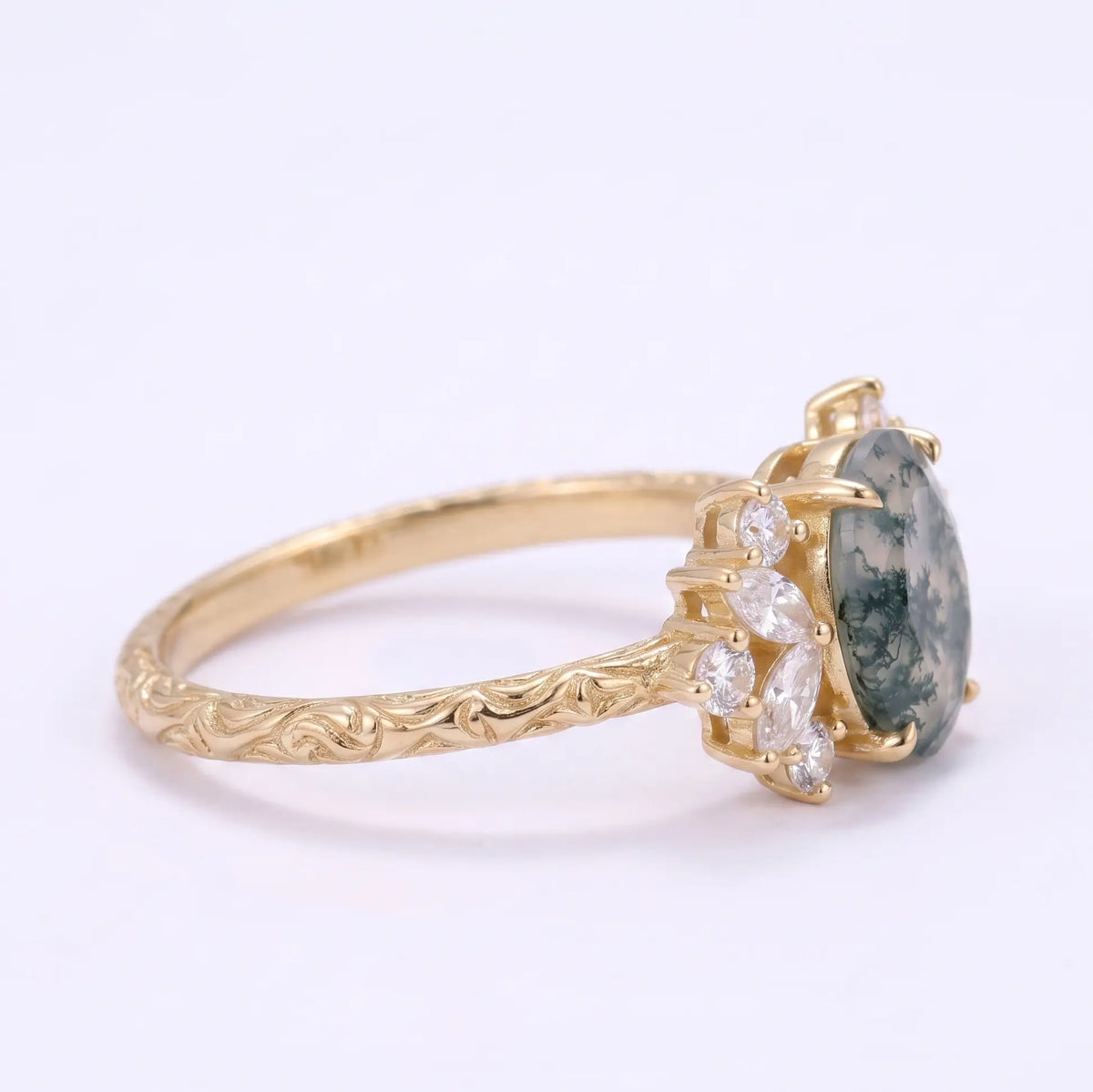 Close-up of engraved band detailing on an oval moss agate engagement ring