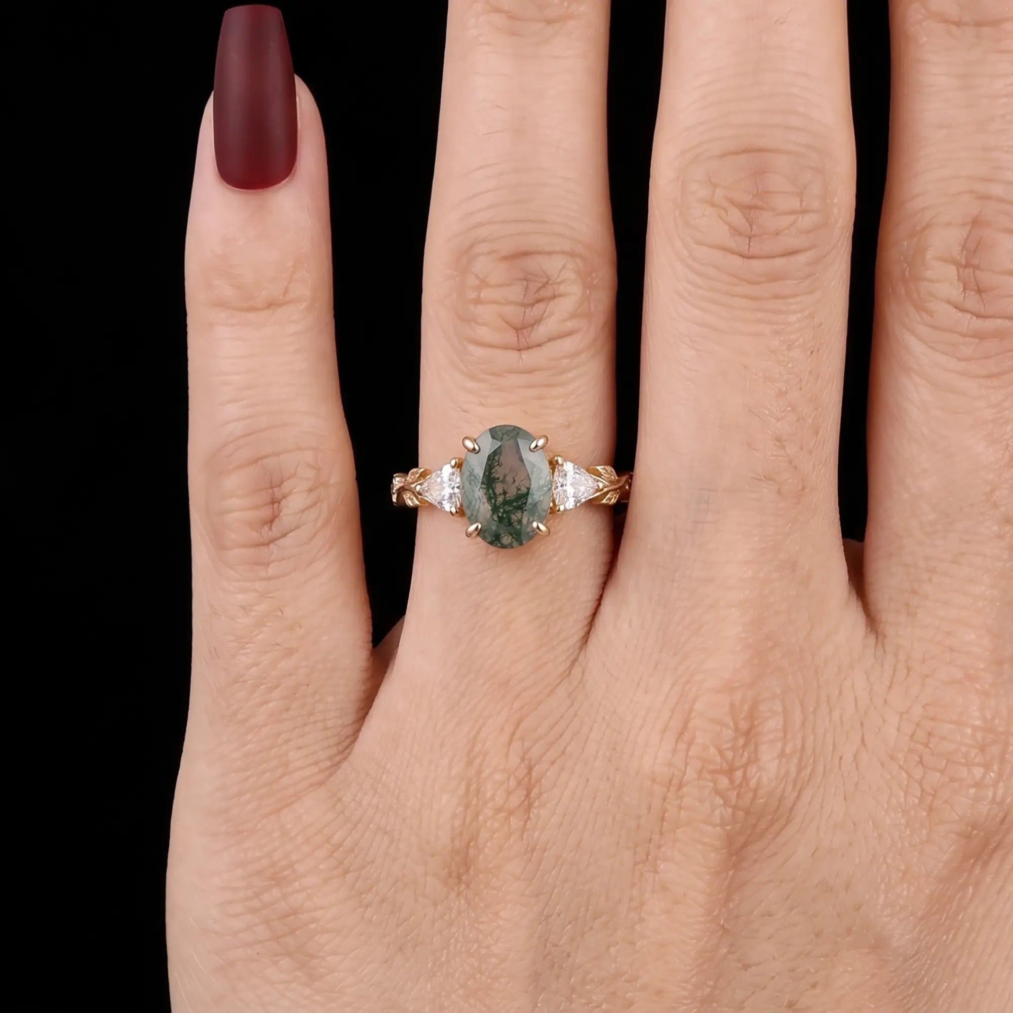 Oval moss agate anniversary ring with leaf band worn on hand