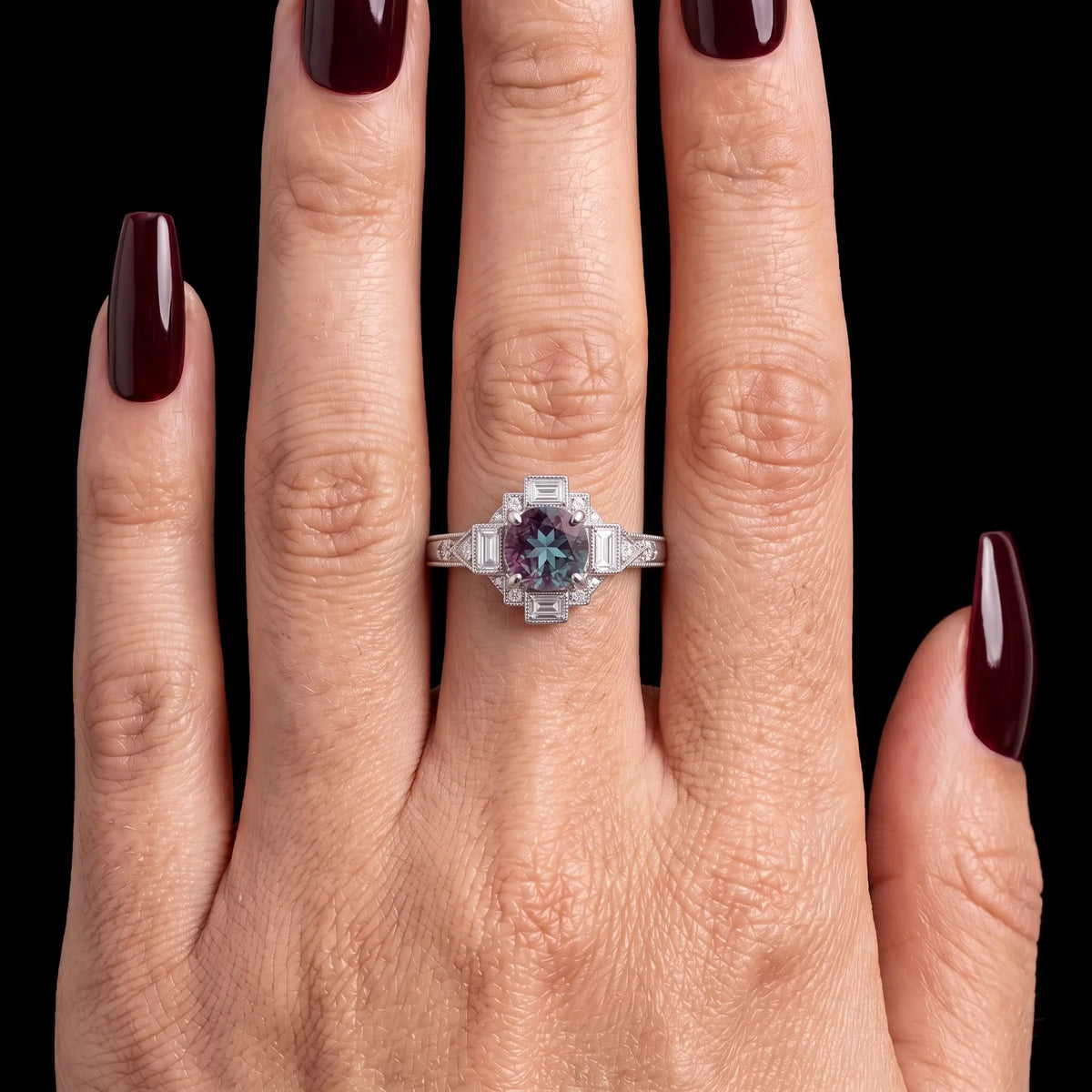 June birthstone alexandrite engagement ring worn on hand showing purple gemstone and geometric vintage white gold setting