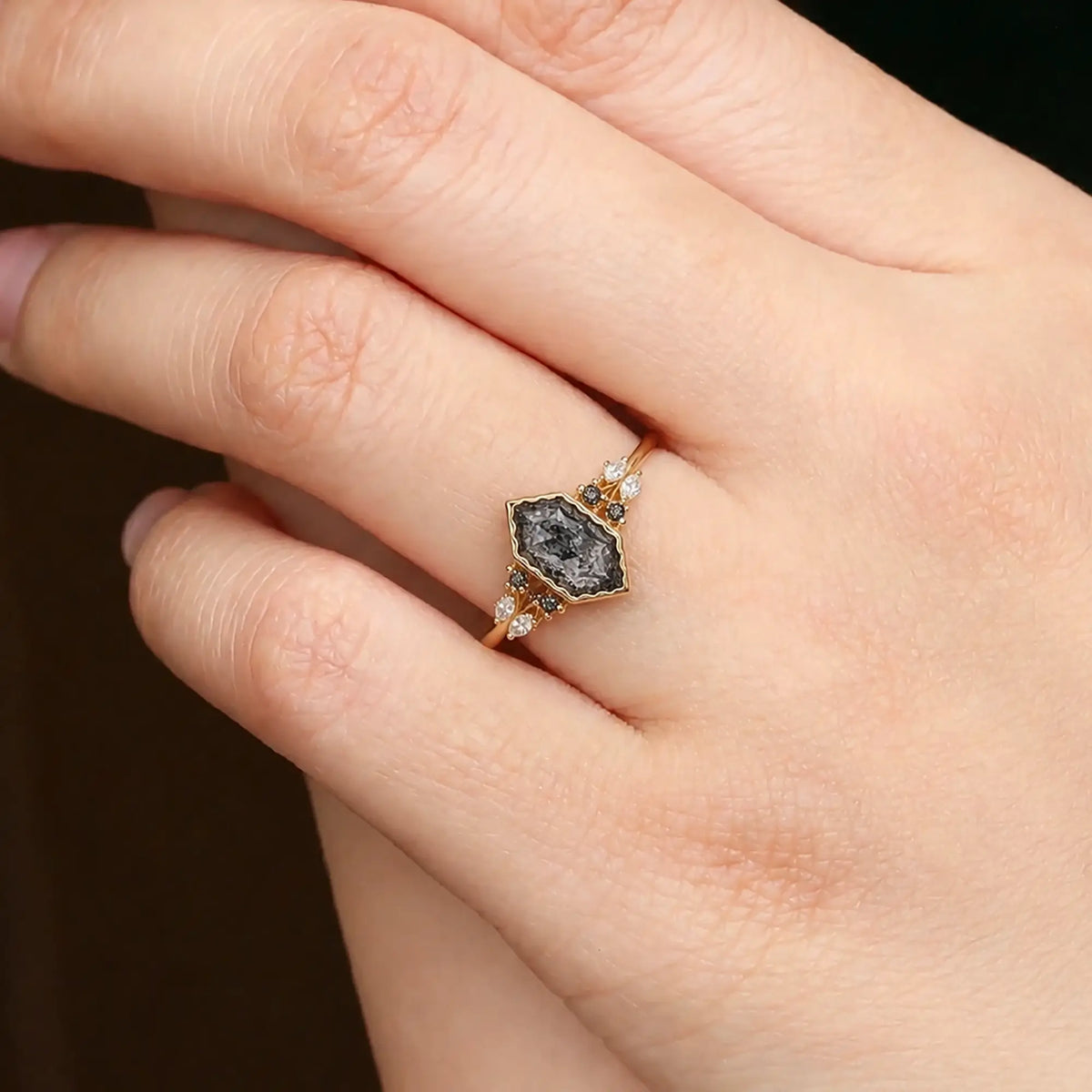 Elongated hexagon salt and pepper diamond ring worn on hand with leaf-inspired accents
