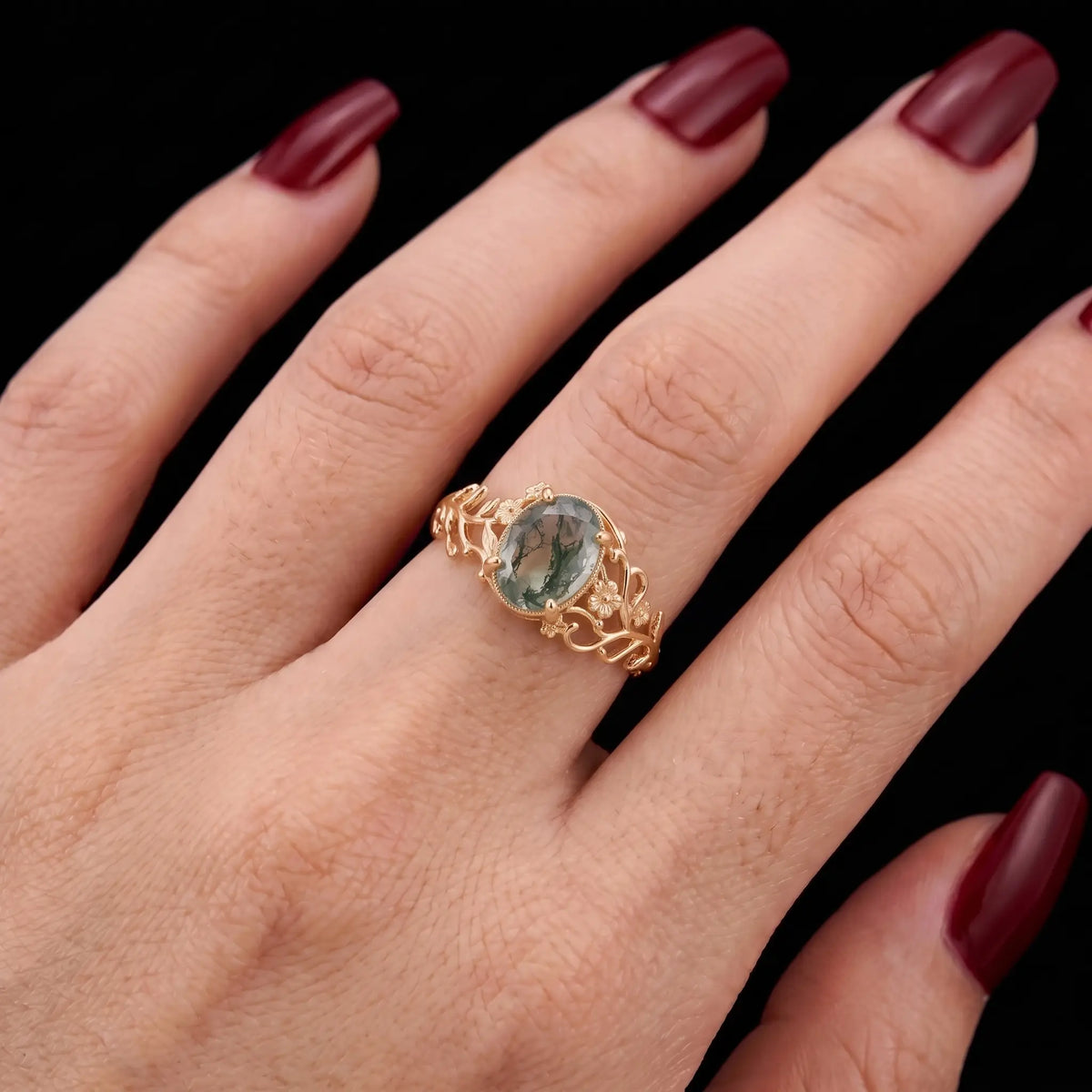 Oval moss agate floral vine engagement ring worn on hand