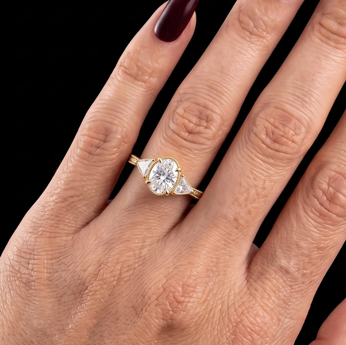 Oval moissanite three stone engagement ring with trillion side stones worn on hand