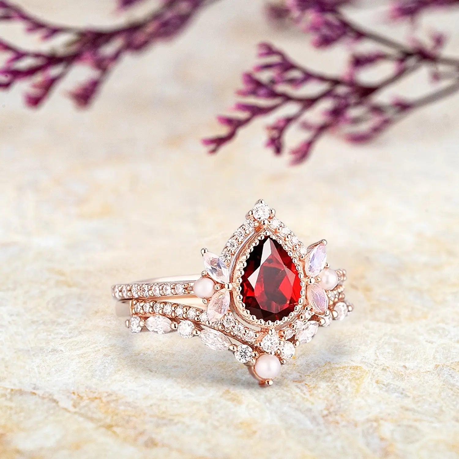 Woman wearing pear ruby engagement ring with pearl moonstone cluster and matching curved wedding band