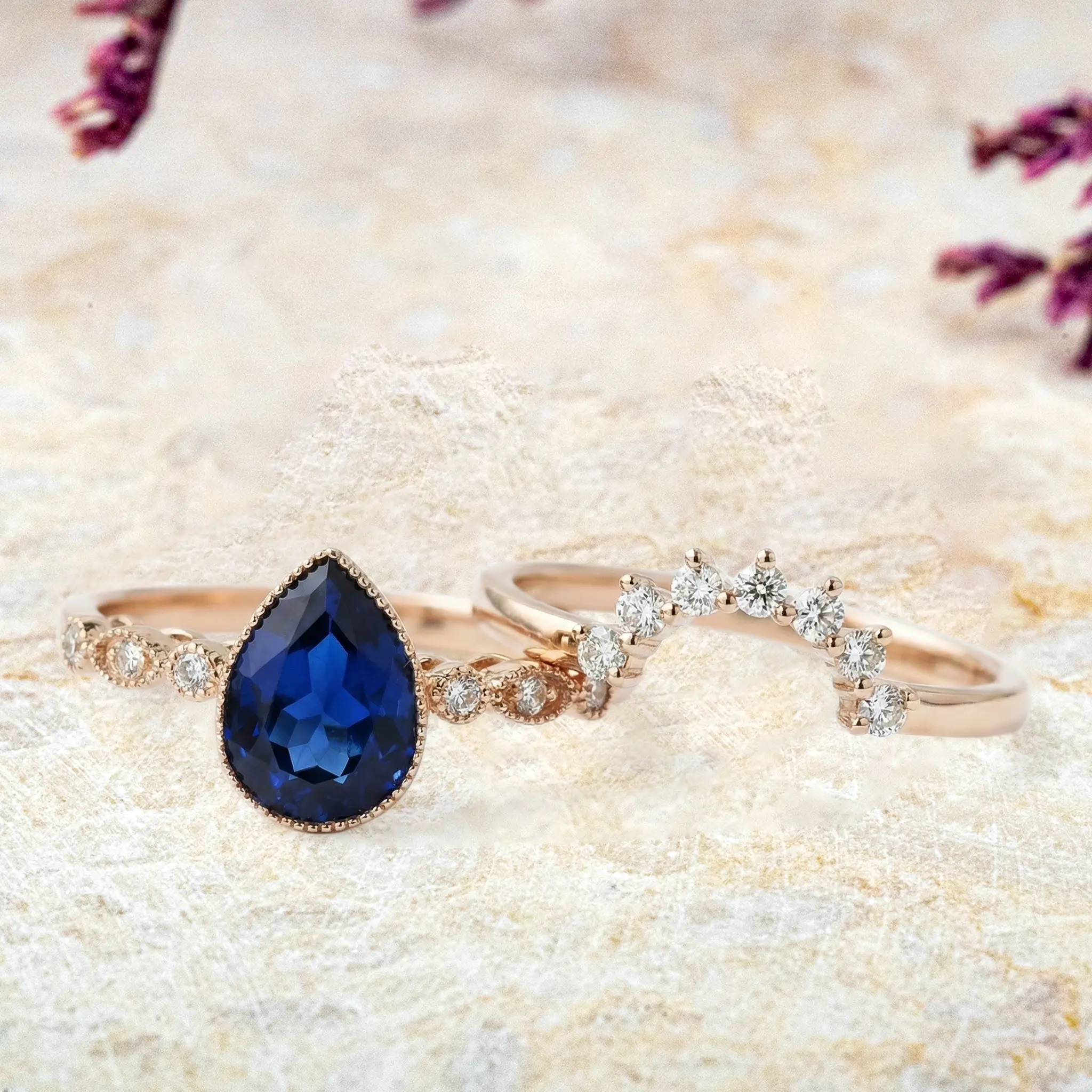 Pear sapphire engagement ring and moissanite wedding band displayed separately showing vintage Art Deco style