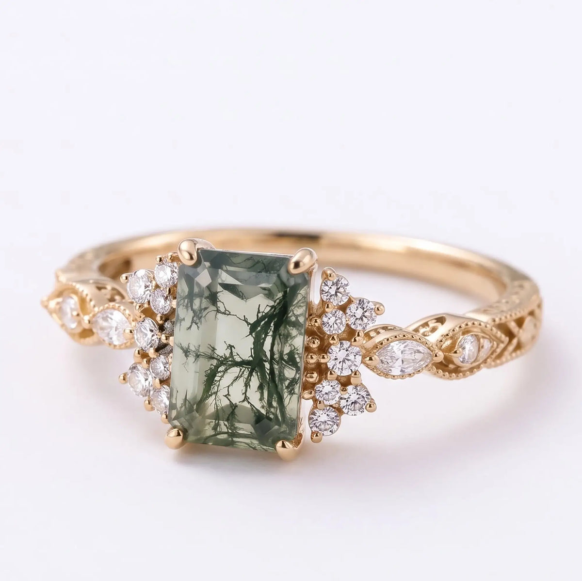 Left angled view of Verdelisse emerald cut moss agate engagement ring showing the vintage cluster setting and elegant gold band details.