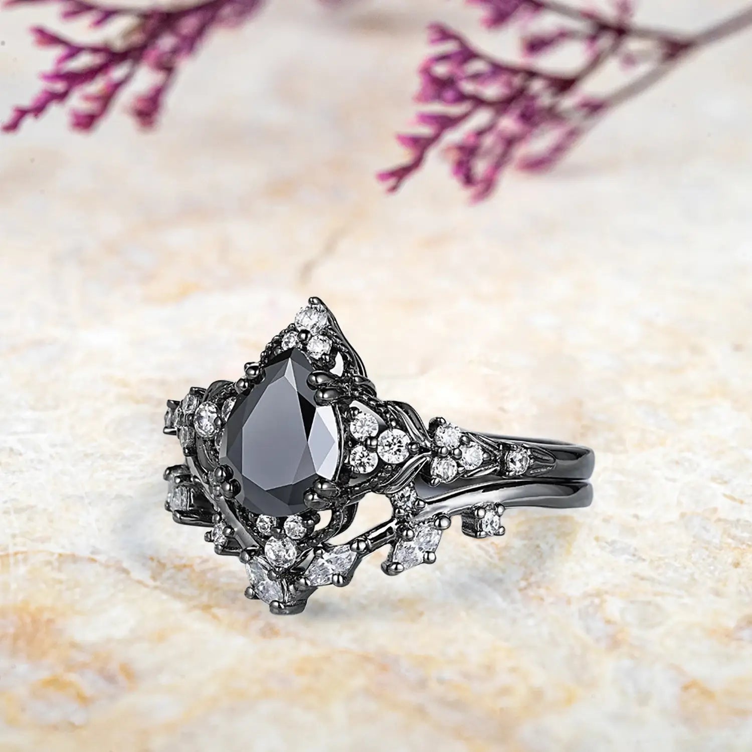 Side view of pear black onyx ring showing nature inspired leaf crown milgrain halo and curved chevron band profile