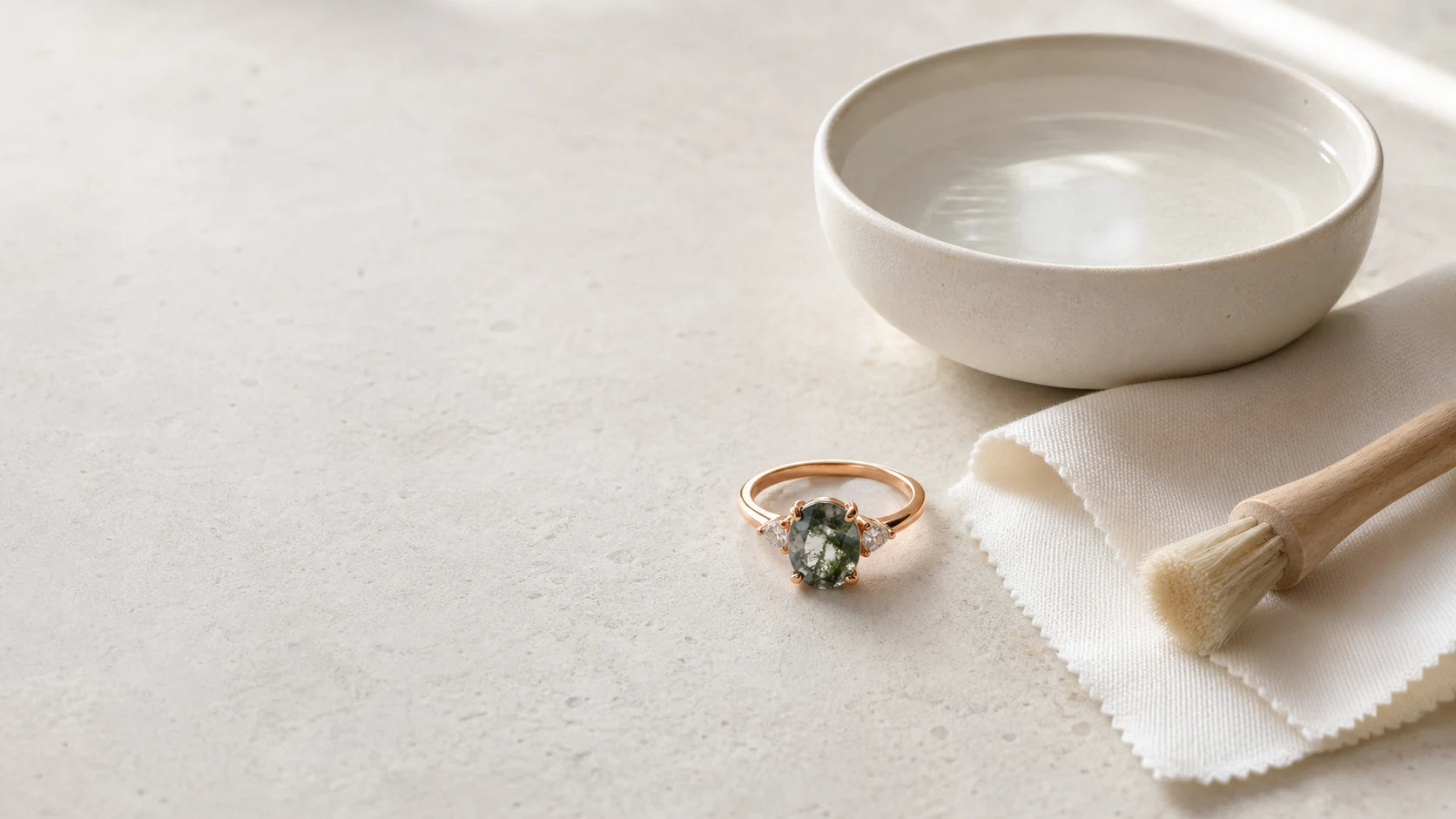 Rose-gold gemstone ring with a soft cloth and cleaning tools